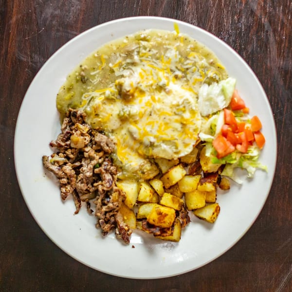 A Rudy's Little Hideaway Mexican dish with green chile, shredded beef, potatoes, and salad.