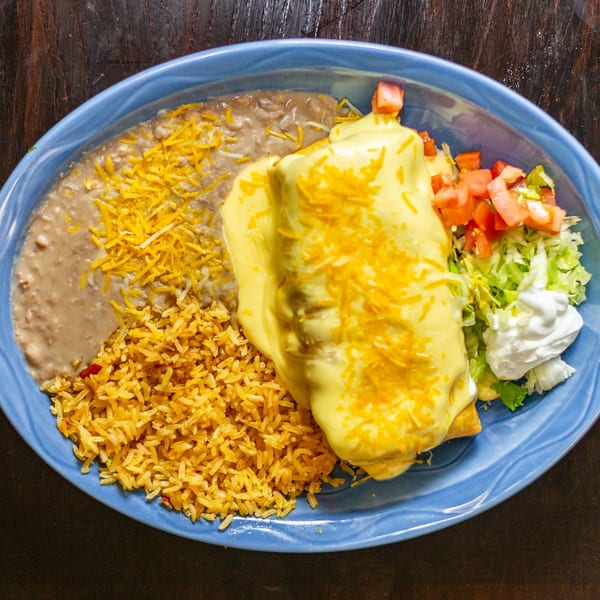 A Rudy's Little Hideaway Mexican food plate with a cheese-covered burrito, rice, beans, and salad.